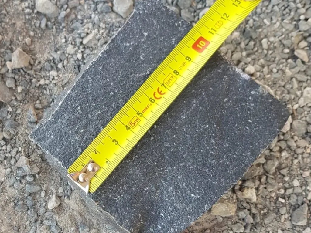 A basalt sett measured against a tape to show its size