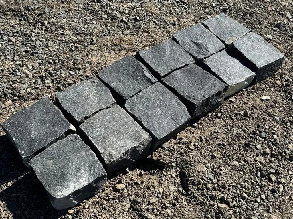 A row of cropped basalt setts showing their split faces and arrises